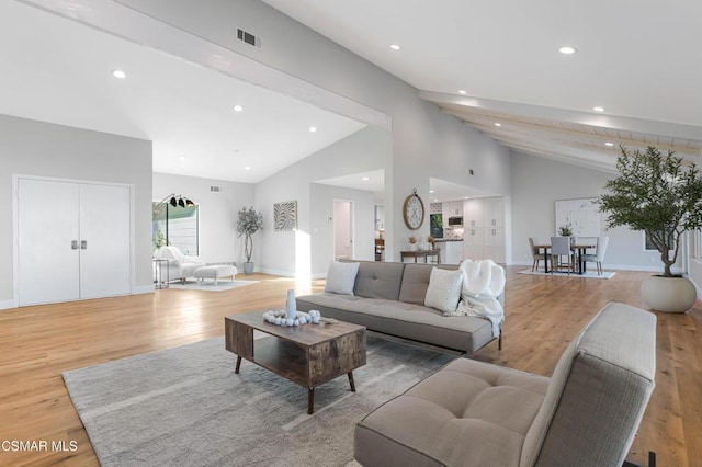 living room featuring high vaulted ceiling and light hardwood / wood-style flooring