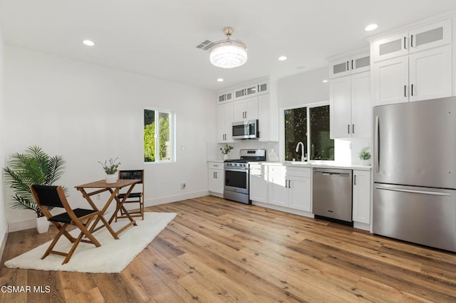 kitchen featuring white cabinets, backsplash, appliances with stainless steel finishes, and light wood-type flooring