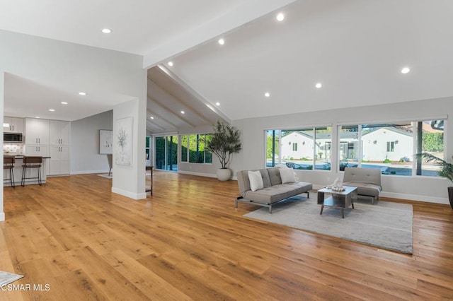 living room featuring lofted ceiling with beams, plenty of natural light, and light hardwood / wood-style flooring