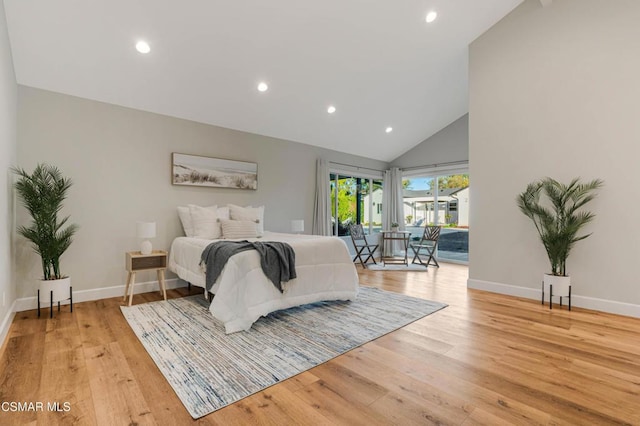 bedroom featuring light hardwood / wood-style flooring, access to outside, and high vaulted ceiling