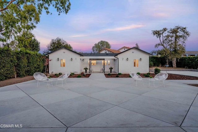 back house at dusk featuring a patio