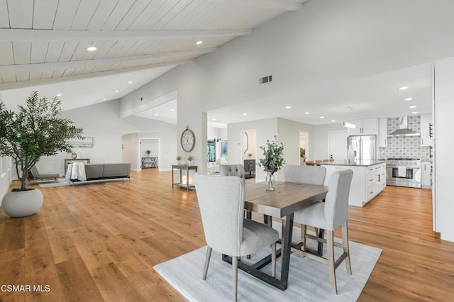 dining area with light hardwood / wood-style flooring and lofted ceiling with beams