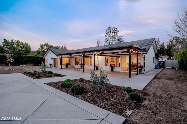 back house at dusk with a patio area