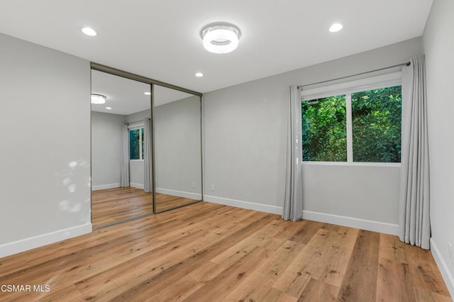 unfurnished bedroom with a closet and light hardwood / wood-style floors