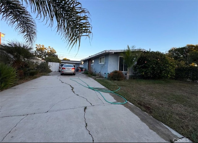 view of property exterior with stucco siding, a lawn, and concrete driveway