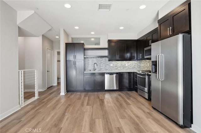 kitchen with decorative backsplash, sink, light wood-type flooring, appliances with stainless steel finishes, and dark brown cabinets