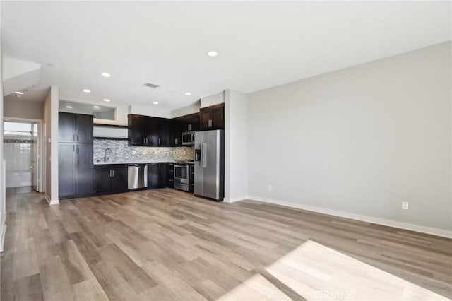 kitchen with appliances with stainless steel finishes, decorative backsplash, light hardwood / wood-style floors, and sink