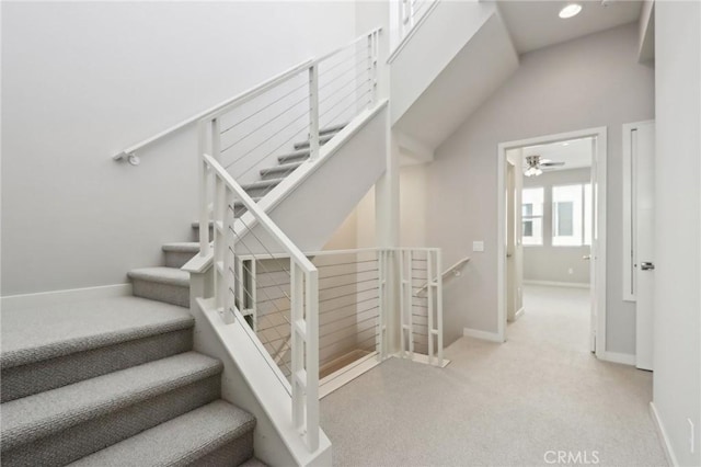 staircase with ceiling fan and vaulted ceiling