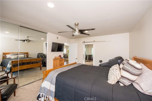 carpeted bedroom featuring a barn door, a closet, and ceiling fan