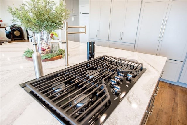 interior details with white cabinets, light stone counters, and stainless steel gas cooktop