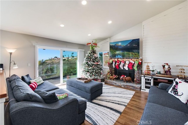 living room featuring hardwood / wood-style flooring, lofted ceiling, a fireplace, and wine cooler