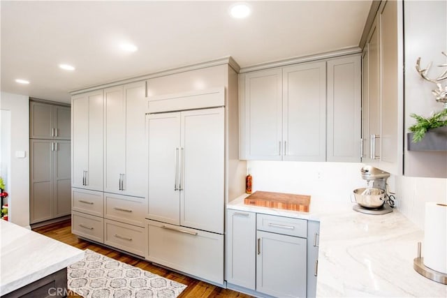 kitchen with paneled fridge, dark hardwood / wood-style flooring, and gray cabinetry