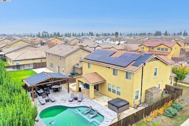 rear view of property featuring a fenced in pool, a gazebo, and solar panels