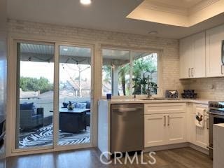 kitchen with white cabinets, dark hardwood / wood-style flooring, stainless steel appliances, sink, and a tray ceiling