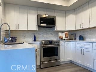 kitchen featuring stainless steel appliances, decorative backsplash, light hardwood / wood-style floors, and white cabinets