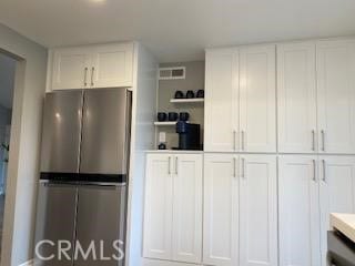 kitchen featuring stainless steel fridge and white cabinetry