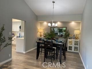 dining room featuring a chandelier, lofted ceiling, and wood-type flooring