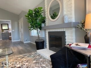 living room featuring lofted ceiling, a fireplace, and hardwood / wood-style flooring