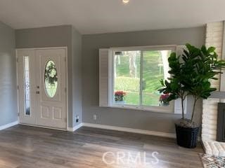 foyer featuring a brick fireplace and wood-type flooring