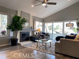 living room featuring ceiling fan, lofted ceiling, a brick fireplace, and hardwood / wood-style floors