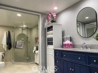 bathroom featuring toilet, a shower with door, and vanity