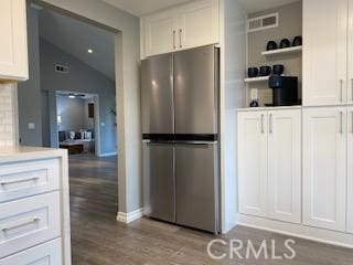 kitchen featuring white cabinets, backsplash, stainless steel refrigerator, and hardwood / wood-style flooring