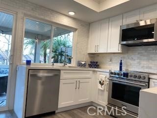 kitchen featuring appliances with stainless steel finishes, white cabinetry, and light hardwood / wood-style floors