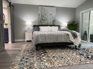 bedroom featuring a barn door and wood-type flooring