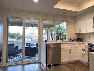 kitchen featuring appliances with stainless steel finishes, wood-type flooring, white cabinetry, sink, and a raised ceiling