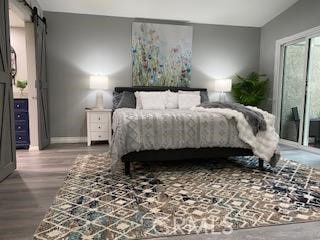 bedroom with a barn door, vaulted ceiling, and hardwood / wood-style floors