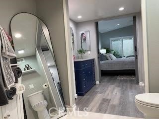 bathroom featuring toilet, vanity, vaulted ceiling, and hardwood / wood-style floors