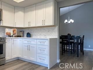 kitchen with light hardwood / wood-style floors, tasteful backsplash, a notable chandelier, stainless steel stove, and white cabinets