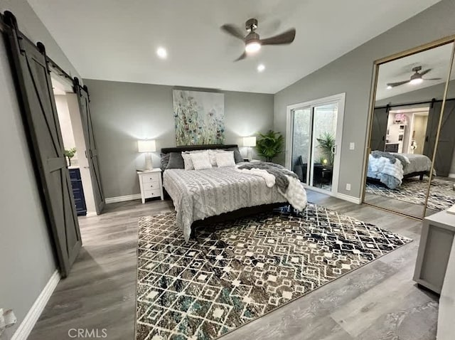 bedroom with access to exterior, vaulted ceiling, hardwood / wood-style floors, and a barn door