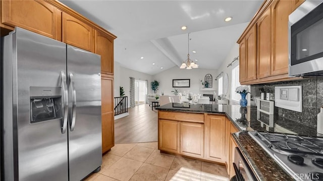 kitchen featuring lofted ceiling, dark stone countertops, light wood-type flooring, tasteful backsplash, and stainless steel appliances