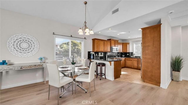 dining room featuring an inviting chandelier, light hardwood / wood-style flooring, and lofted ceiling