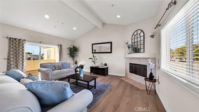 living room with vaulted ceiling with beams, light hardwood / wood-style floors, and a fireplace