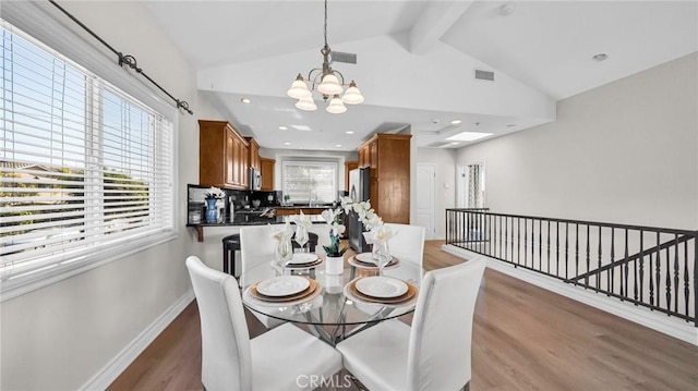 dining room featuring vaulted ceiling with beams, plenty of natural light, dark wood-type flooring, and an inviting chandelier