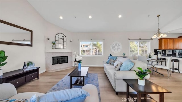 living room featuring a chandelier, a fireplace, a healthy amount of sunlight, and lofted ceiling