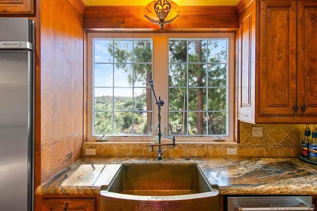 kitchen with stainless steel appliances, sink, backsplash, and stone counters