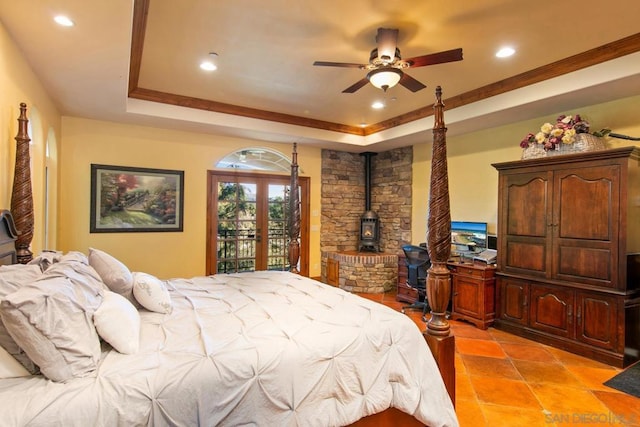 bedroom with ceiling fan, a tray ceiling, access to outside, french doors, and a wood stove