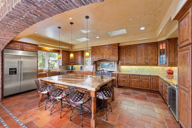 kitchen featuring a large island, hanging light fixtures, a skylight, high quality appliances, and a kitchen bar