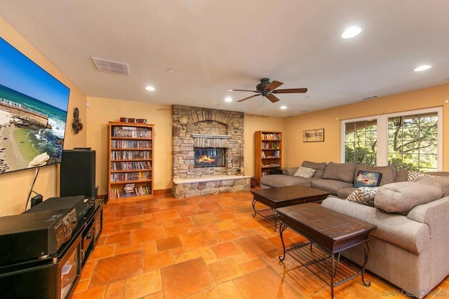 living room featuring ceiling fan and a stone fireplace