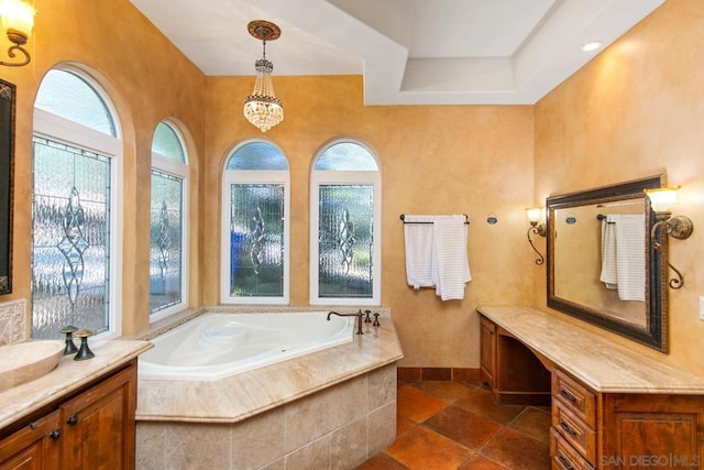 bathroom featuring a relaxing tiled tub, plenty of natural light, and vanity