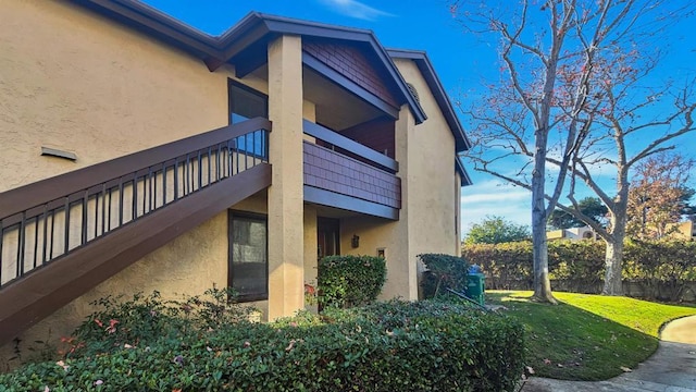 view of side of home featuring a lawn and a balcony