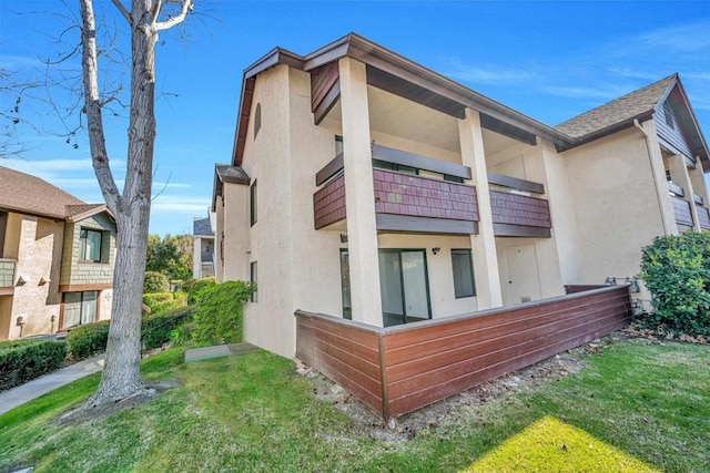 back of property featuring a balcony and a lawn