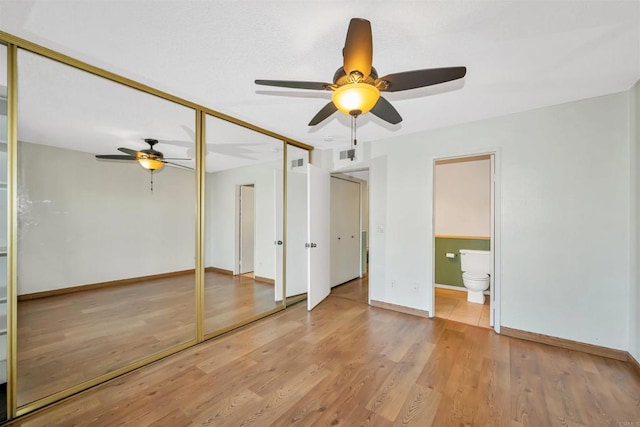 unfurnished bedroom with hardwood / wood-style flooring, ensuite bath, and ceiling fan