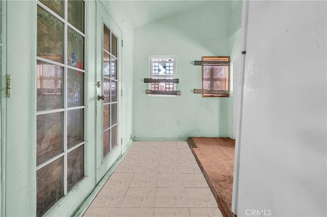 hallway featuring light tile patterned flooring and lofted ceiling