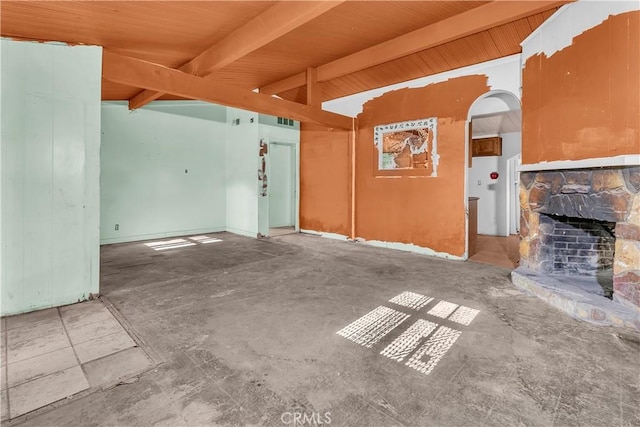 unfurnished living room featuring concrete flooring, a fireplace, beamed ceiling, and wooden ceiling