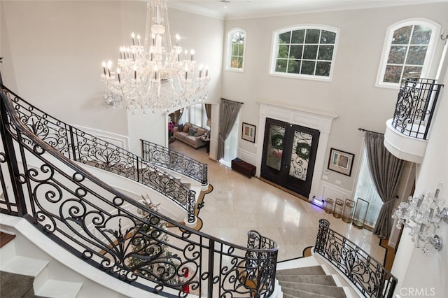 foyer entrance featuring french doors, a notable chandelier, ornamental molding, and a towering ceiling