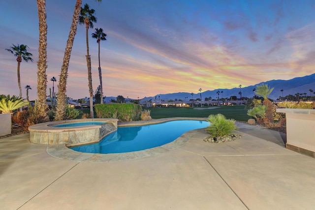 pool at dusk with a patio area, an in ground hot tub, and a mountain view